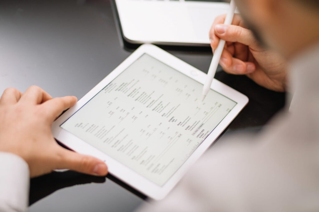 A professional reviewing invoices and asset data on a digital tablet, showcasing streamlined operations with Nucleus Service software.