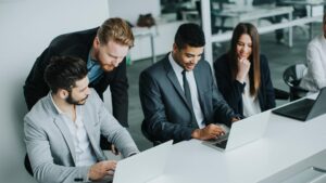 Business team collaborating on laptops using Nucleus Service Software to manage jobs and improve efficiency.