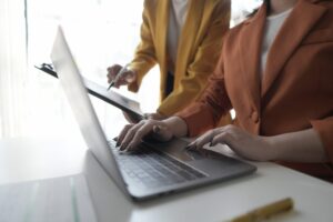 Two professionals reviewing financial data on a laptop, using job costing software for service businesses to track costs and improve profitability