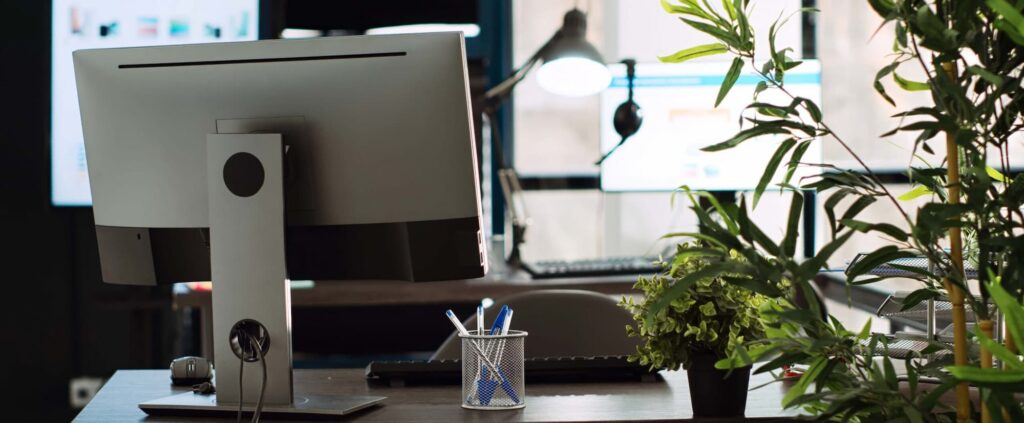 Modern office workspace with computer and plants, representing efficiency with Kyocera office equipment software.