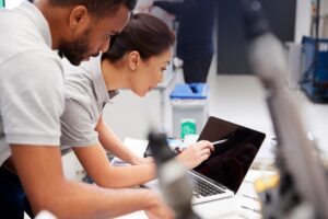 Engineers collaborating on laptop using business automation tools to improve operational efficiency.