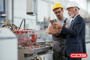 Supervisor and worker reviewing tablet data on factory floor—improving warehouse operations with technology and teamwork