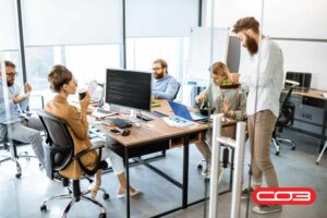 Team in modern office collaborating on computers with CO3’s Field Service Management Software reviews discussed for business efficiency