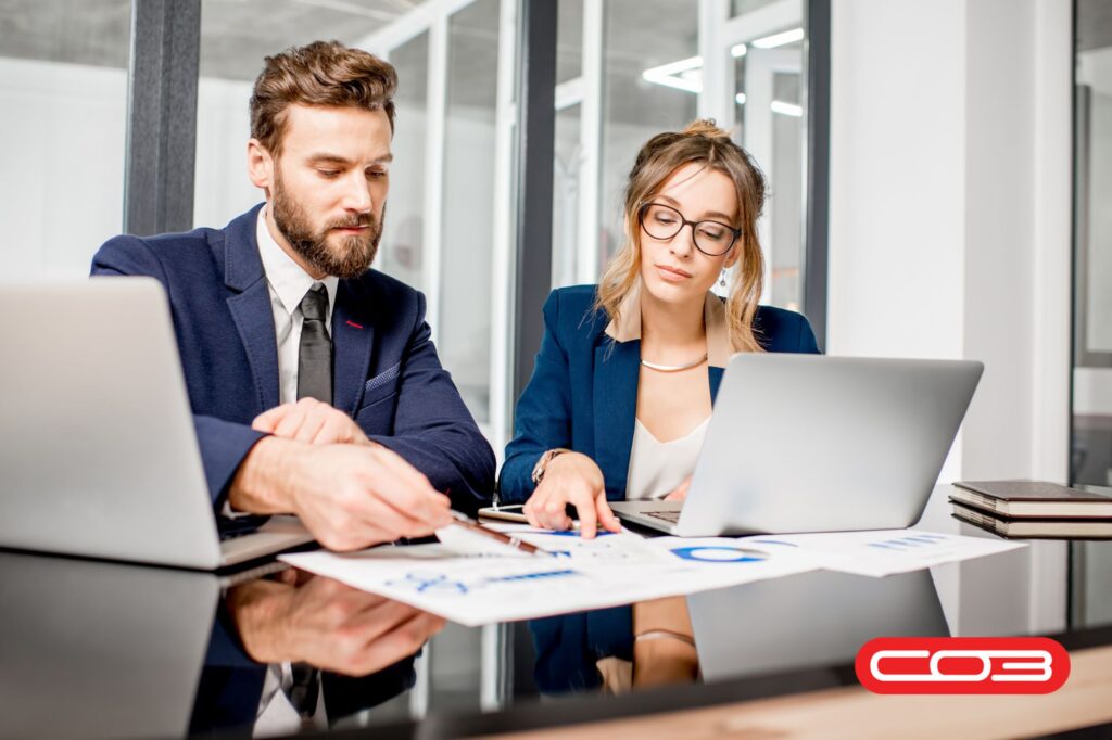 Business team discussing reports on laptops – best field service management software UK for customer retention and smart operations