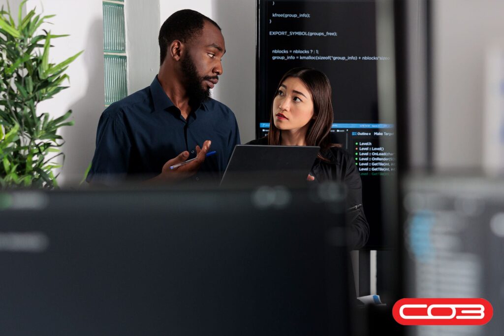 Team collaborating in a tech office while discussing data on-screen, illustrating the use of Operations Management Software