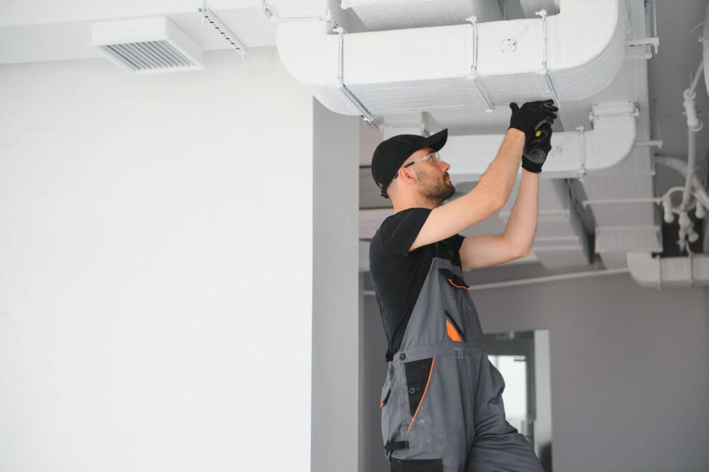 Technician repairing an HVAC system using HVAC field service software insights to improve efficiency and maintenance accuracy.