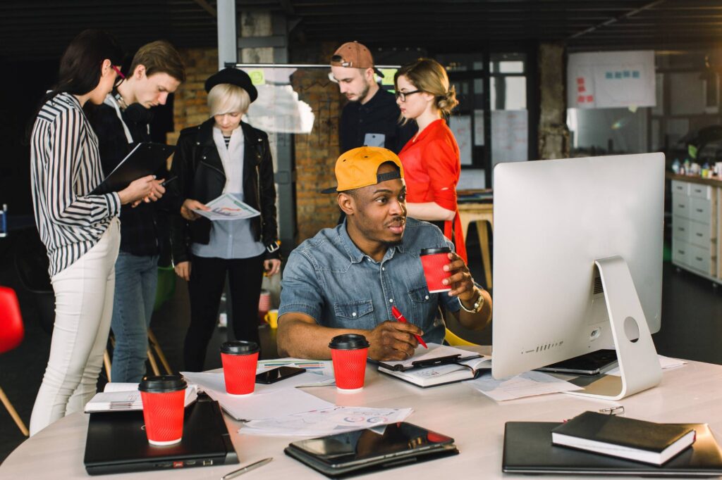 A team collaborating in a modern office as one worker reviews data on a computer, illustrating the hidden cost of spreadsheets and the value of automation.