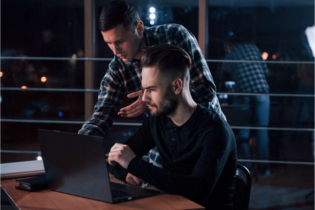 Two professionals reviewing data on a laptop, using field service management software to coordinate operations and improve decision-making.