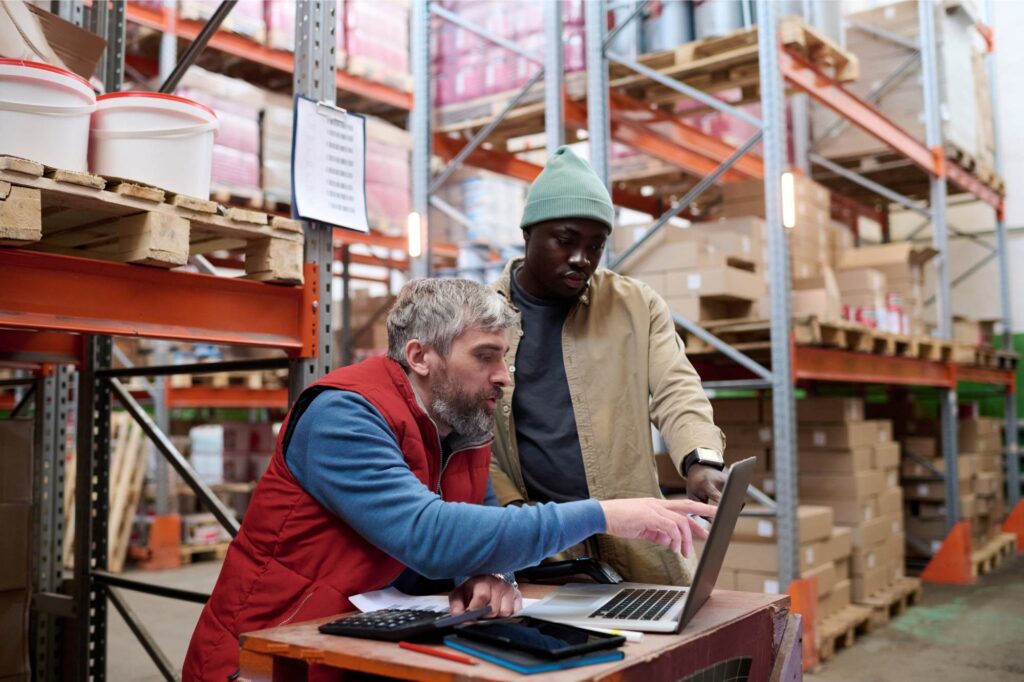 Inventory Management Software helping warehouse staff monitor stock levels and improve inventory visibility using a laptop.